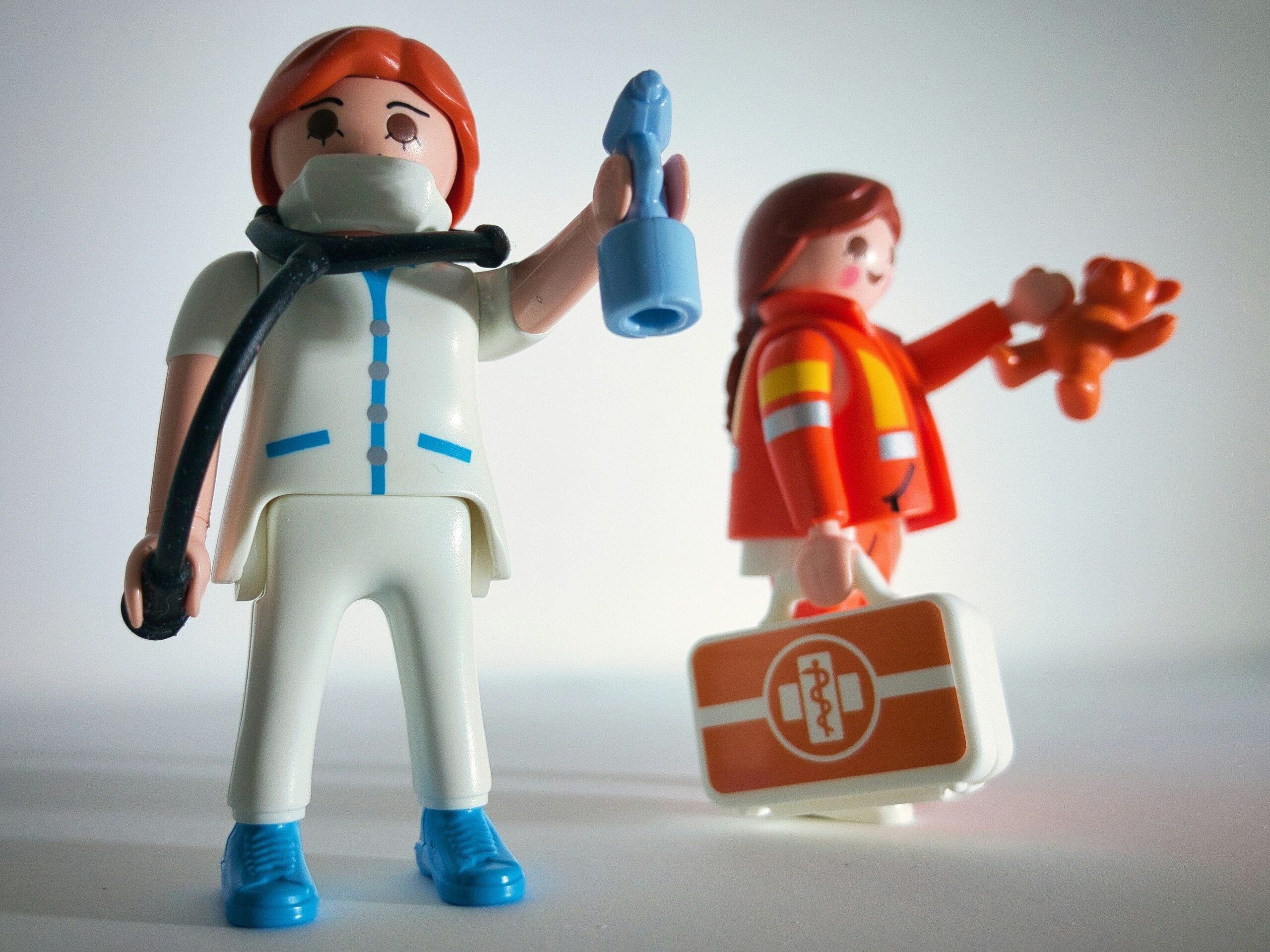 Toy figurines depicting a healthcare worker holding a vaccine vial and an emergency responder carrying a medical kit.